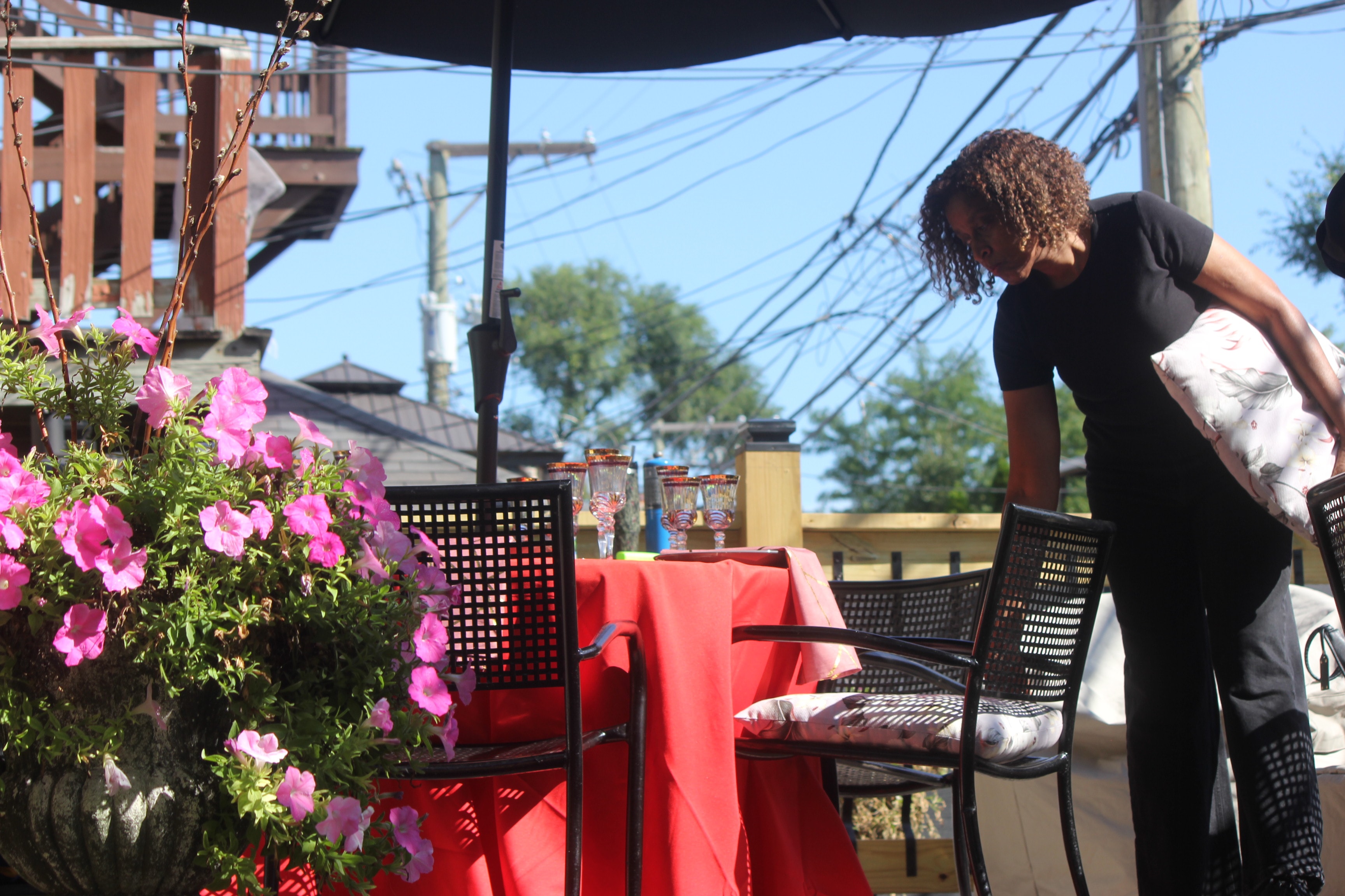 Staff member setting up outdoor table with pink flowers and red tablecloth